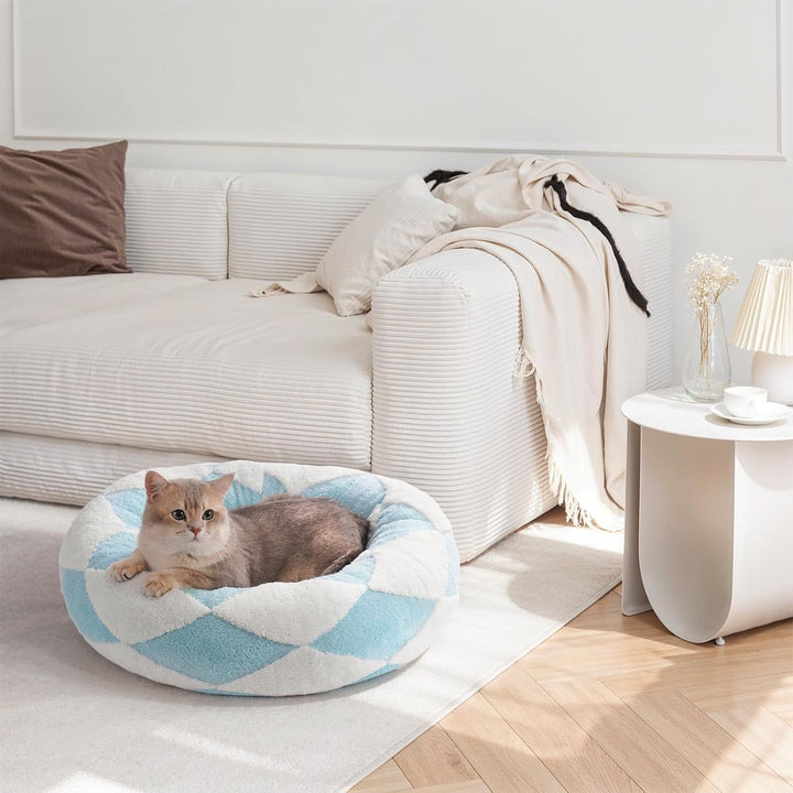Cat lying on a checkered pet bed in a cozy living room.