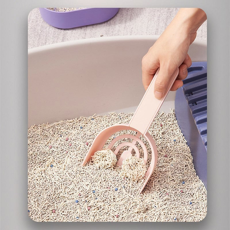 Person using a pink scoop to clean a cat litter box filled with light-colored litter